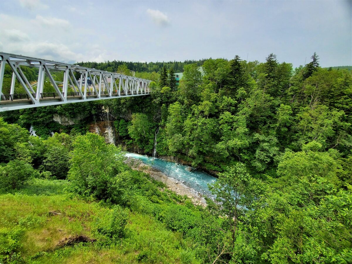 鉄橋と緑に囲まれる白ひげの滝周辺の川の風景